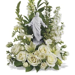 White floral arrangement with a small religious statue in the center