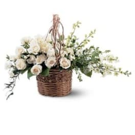 White roses in a wicker basket with trailing greenery