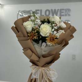 Bouquet of white roses and orange daisies wrapped in brown paper
