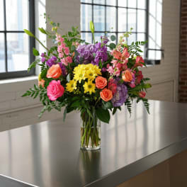 Mixed bouquet of roses, hydrangeas, and daisies in a clear glass vase