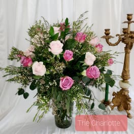 Pink and white roses in a glass vase with greenery