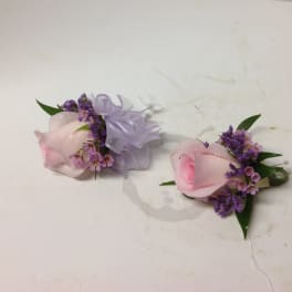 Two pink rose boutonnieres with purple filler and ribbon bows