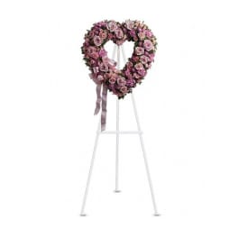 Heart-shaped pink rose wreath on a white easel with ribbon