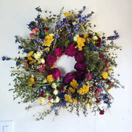 Circular wreath of mixed dried flowers in blue, yellow, pink, and purple