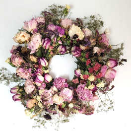 Dried floral wreath with pink and purple blooms on a white background