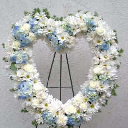 Heart-shaped white and blue floral wreath on a stand