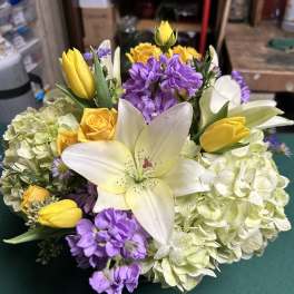 Bouquet of white lilies, yellow tulips, purple flowers, and pale hydrangeas