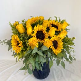 Yellow sunflowers and roses in a dark blue vase