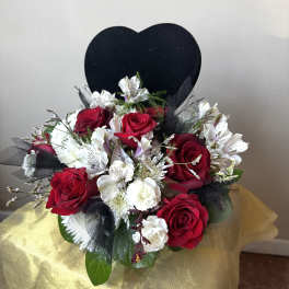 Red roses and white flowers in a bouquet with a black heart backdrop