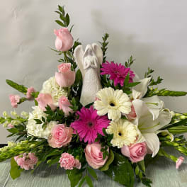 Pink and white floral arrangement with an angel figurine