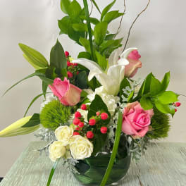 Pink and white roses with lilies in a glass vase