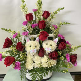 Flower arrangement with red roses and two cat faces in a white basket