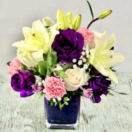 Bouquet of lilies, roses, and carnations in a square glass vase
