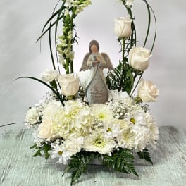 White floral sympathy arrangement with an angel figurine