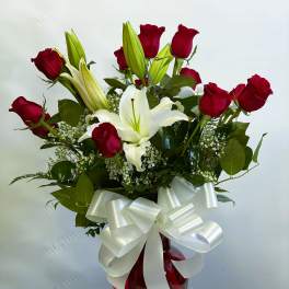 Red roses and white lilies in a red vase with a white bow