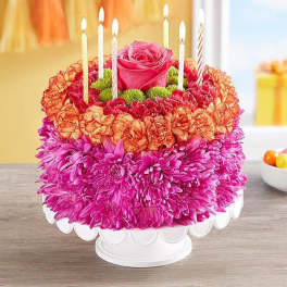 Round floral cake with candles and a pink rose centerpiece