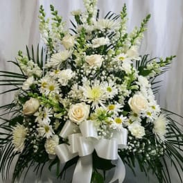 White floral funeral spray with roses, daisies, and a satin bow