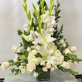 Tall white floral arrangement in a square glass vase