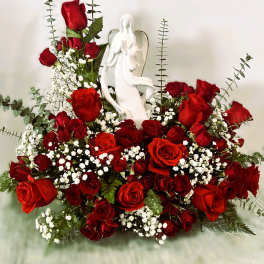 Red roses arranged around a white angel figurine