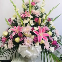 Large pink and white floral arrangement with lilies and roses in a white vase