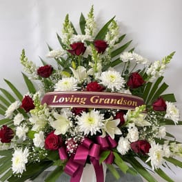 Sympathy spray with red roses, white lilies, and a memorial ribbon