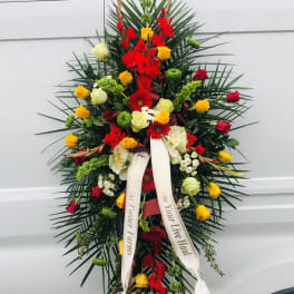 Standing funeral spray with red, yellow, and white flowers on a ribboned easel