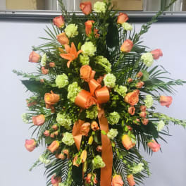 Tall standing floral spray with peach roses and green carnations on an easel