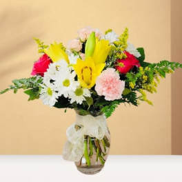 Mixed bouquet with yellow lilies, white daisies, pink roses, and carnations in a glass vase