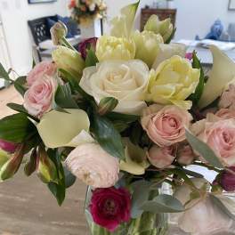 Mixed bouquet of pink, white, and yellow flowers in a clear glass vase