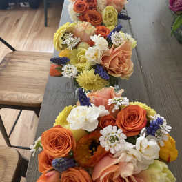Rows of colorful flower arrangements in clear glass containers on a table
