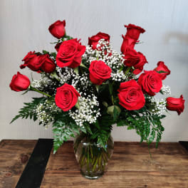 Red roses arranged in a clear glass vase with baby's breath