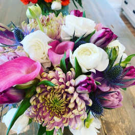 Bouquet of pink, white, and purple flowers with spiky blue accents
