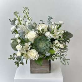 White floral arrangement in a wooden box with a green succulent centerpiece