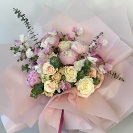 Pink and white bouquet of roses and peonies wrapped in pale pink paper