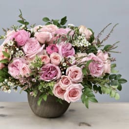 Pink roses arranged in a round vase with greenery