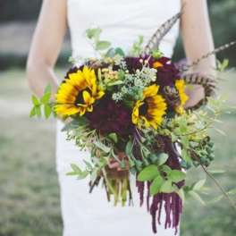 Bride holding a bouquet with sunflowers and trailing greenery