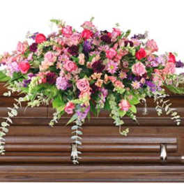 Pink and purple floral spray on a wooden casket