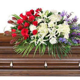 Floral casket spray with red, white, and purple flowers on a wooden casket