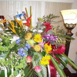 Large tropical flower arrangement with bright mixed blooms and broad leaves