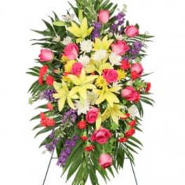 Standing floral spray with pink roses, yellow lilies, and purple accents