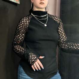 Person wearing a black lace-sleeve top and jeans