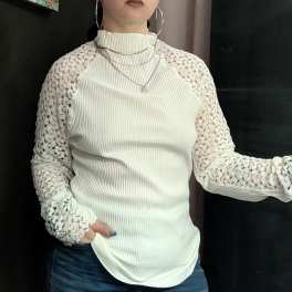 Woman wearing a cream ribbed top with lace sleeves and jeans