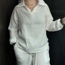 Person wearing a white textured shirt and pants against a dark background