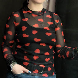 Person wearing a black sheer top with red heart pattern