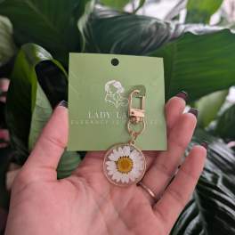 Daisy keychain charm on a green card held in a hand