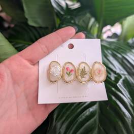 Hand holding a card with four floral resin hair clips
