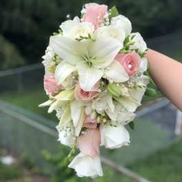 White lilies and blush roses in a hand-held bouquet