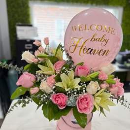 Pink and white floral arrangement with a baby shower balloon