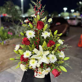 Tall floral arrangement with red roses, white lilies, and white daisies in a vase
