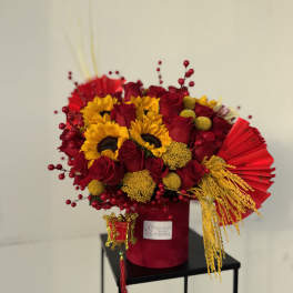 Red and yellow floral arrangement in a red vase with decorative accents
